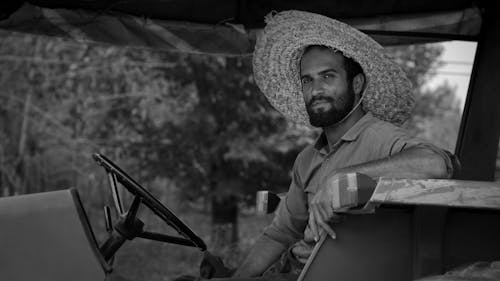 Grayscale Photo of Man Wearing Straw Hat and Button Up Shirt