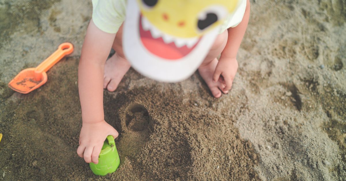 A child playing joyfully with sand toys on the beach, creating a fun and playful atmosphere.