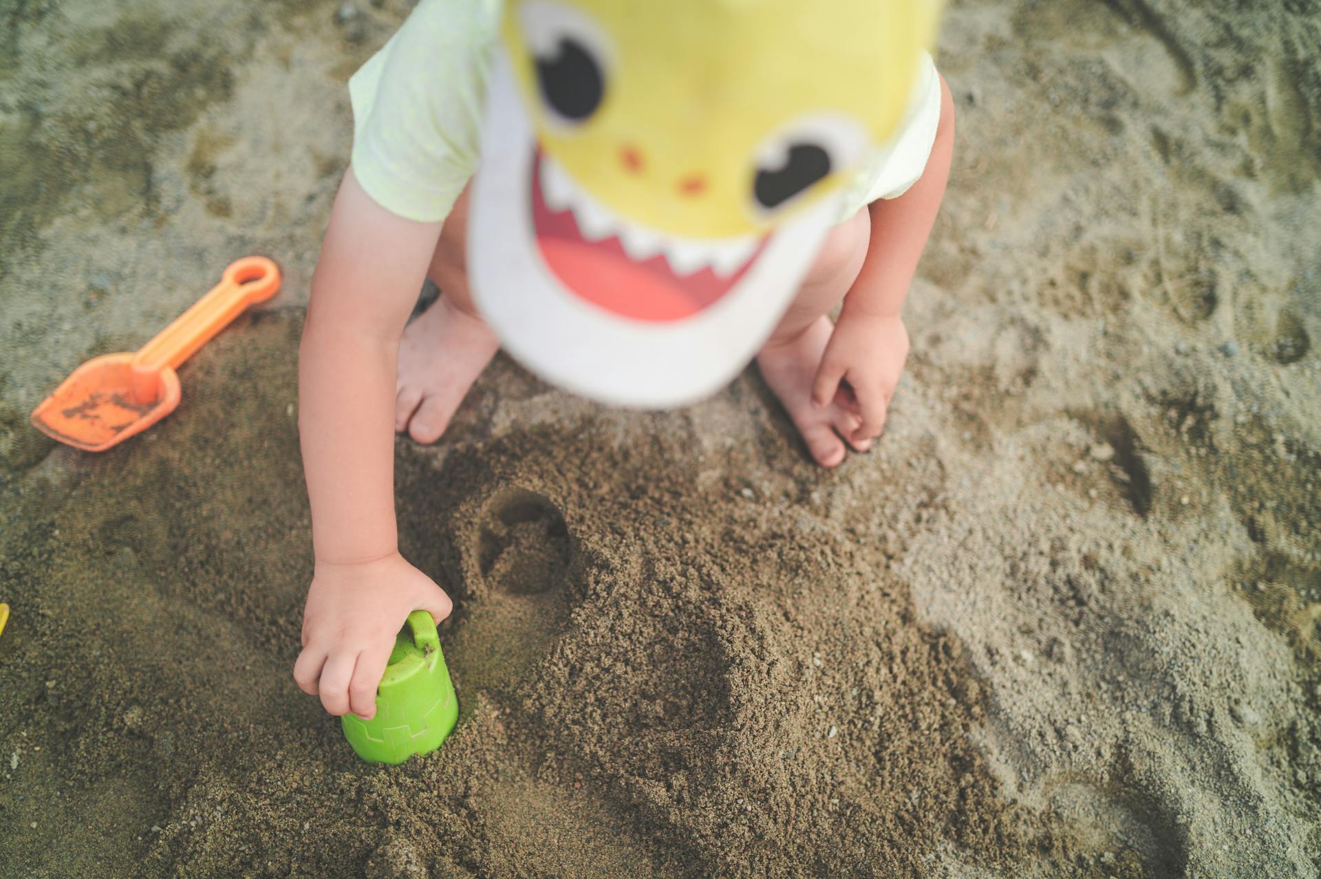 A child playing joyfully with sand toys on the beach, creating a fun and playful atmosphere.