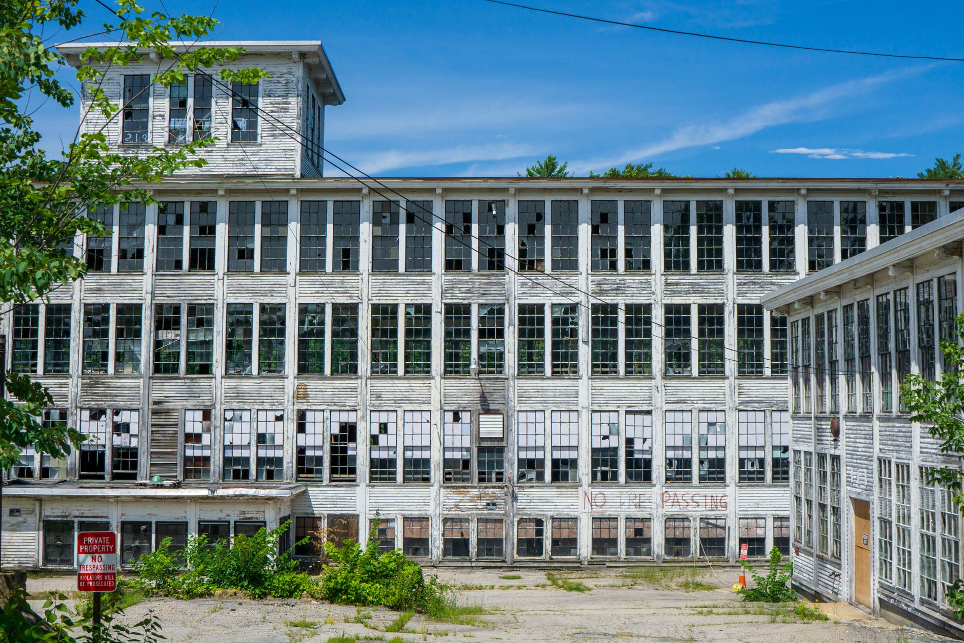 A decaying multi-storey building with broken windows under a blue sky, embodying urban decay.