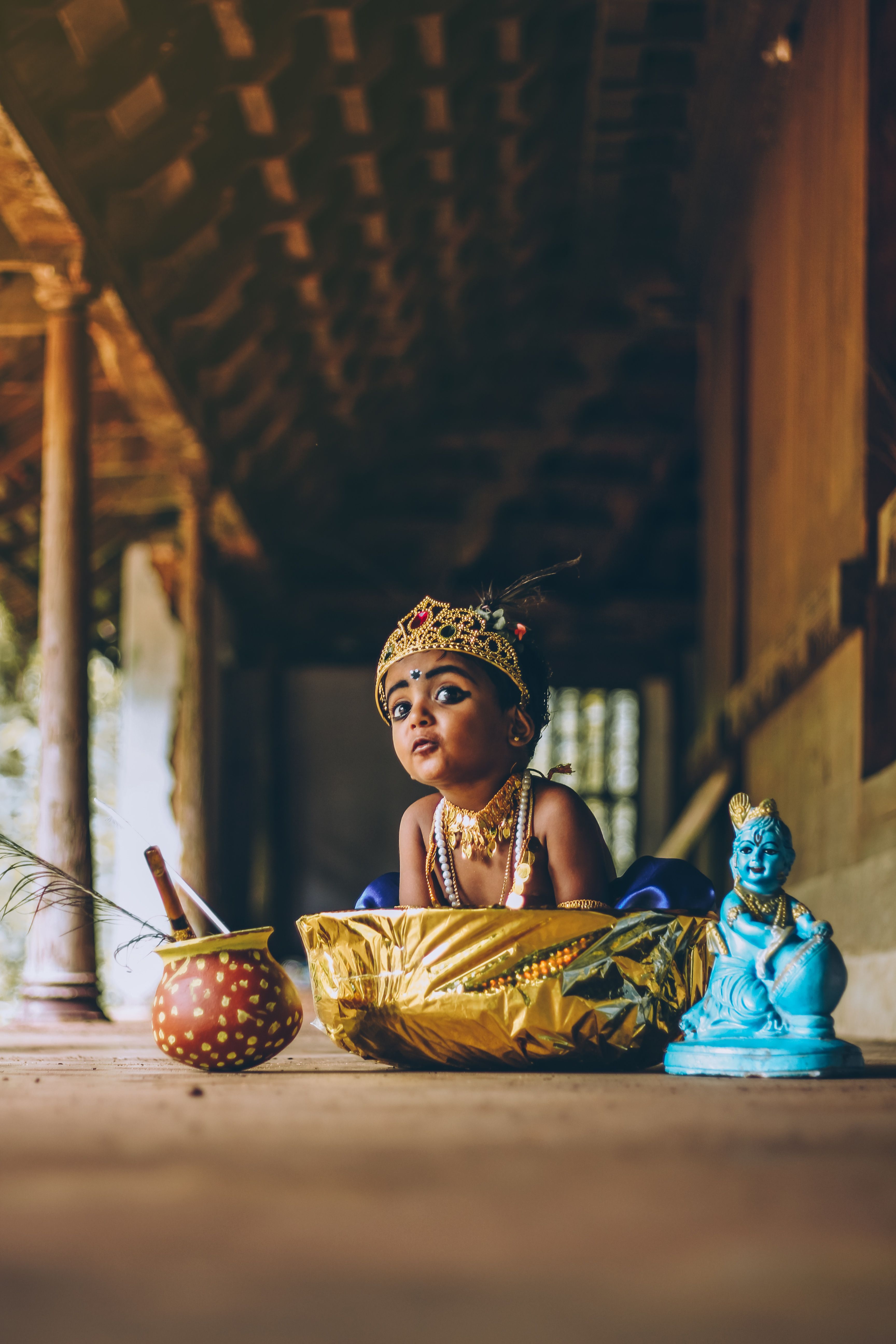 Charming image of a child in traditional attire with a Buddha statue and basket, conveying cultural richness.