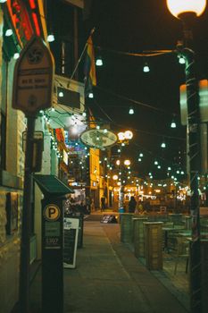 City street at night adorned with festive lights and vibrant urban atmosphere.