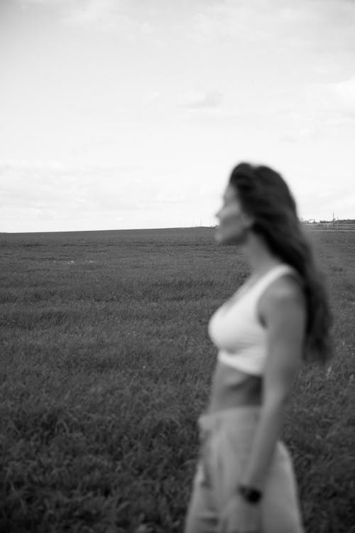 Woman in White Tank Top Standing on Grass Field