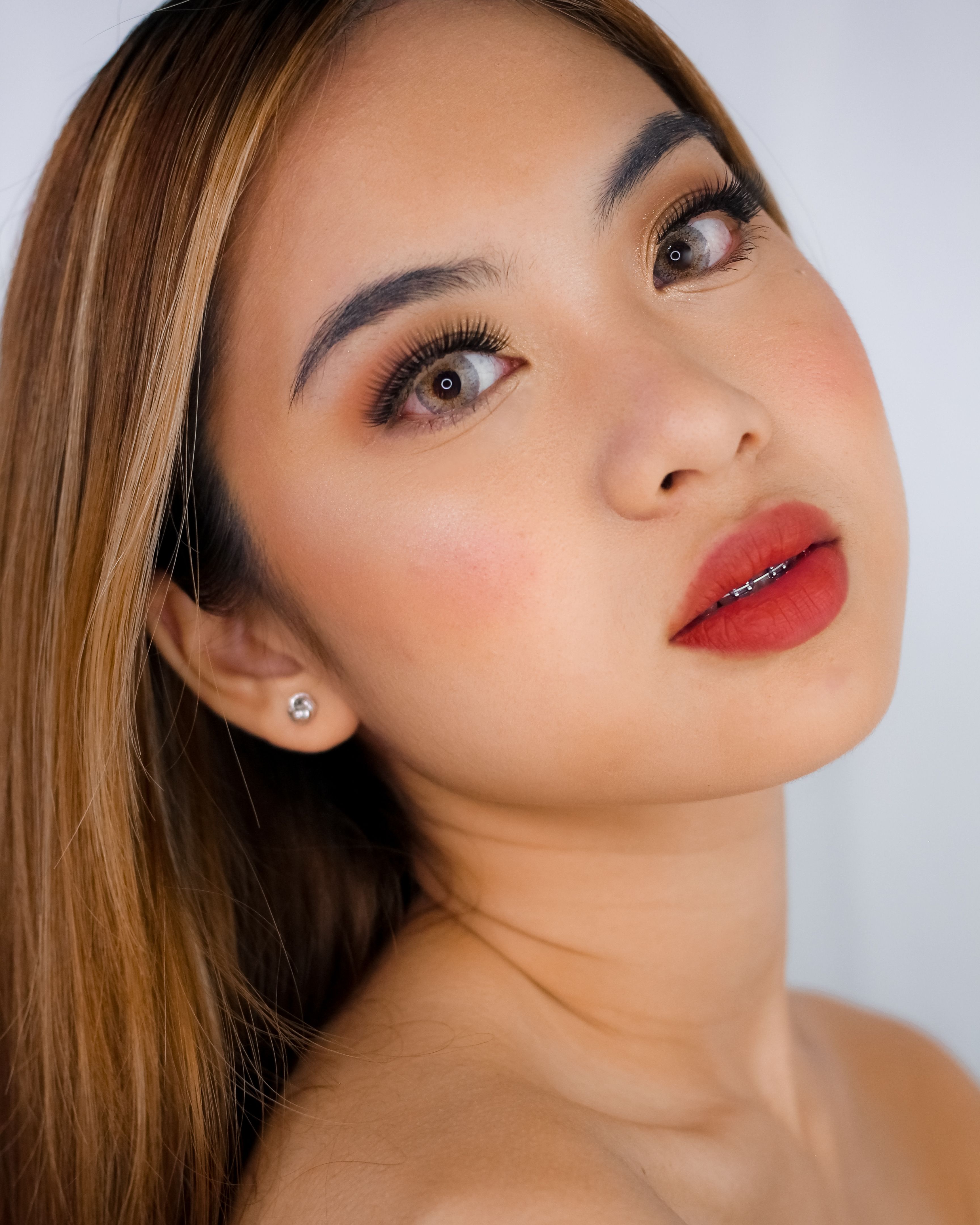 Beautiful studio portrait of a young woman with striking makeup and captivating gaze.