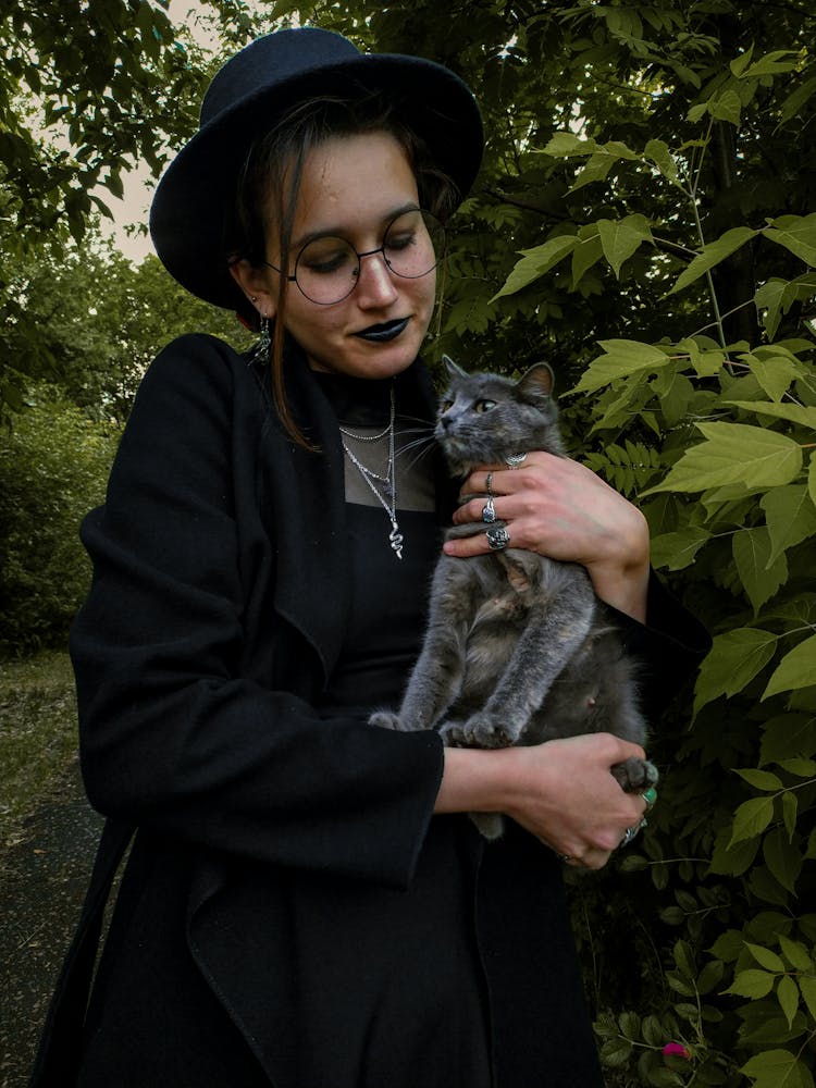 Woman In Black Coat Holding Silver Tabby Cat