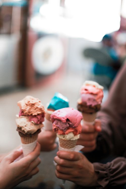 Free Hands holding vibrant ice cream cones creating a joyful summer vibe. Stock Photo
