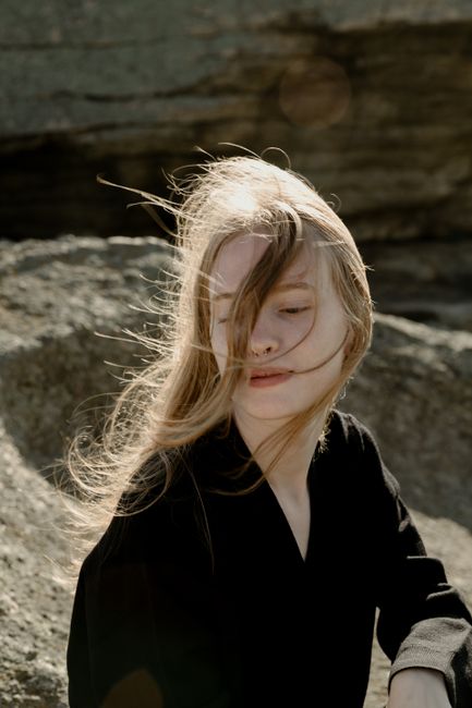 Elegant outdoor portrait of a woman in black with windblown hair.