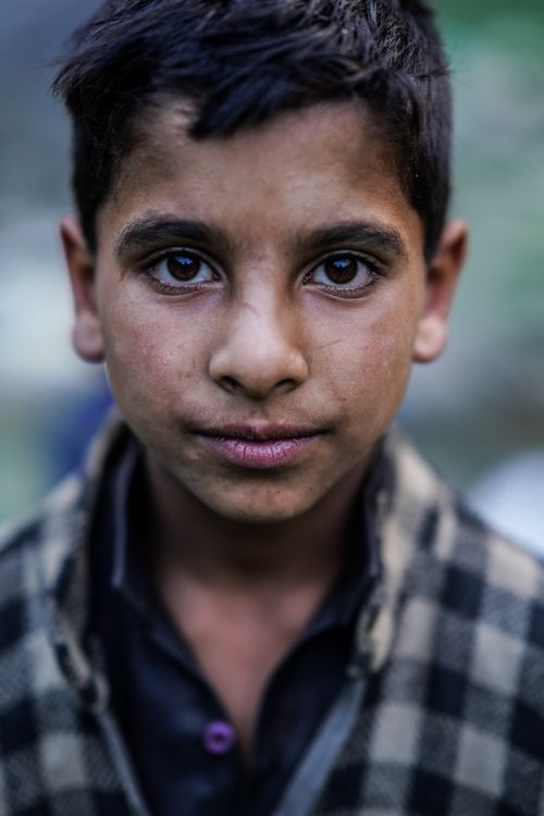 Free A serious young boy with a thoughtful expression captured in a close-up portrait outdoors. Stock Photo