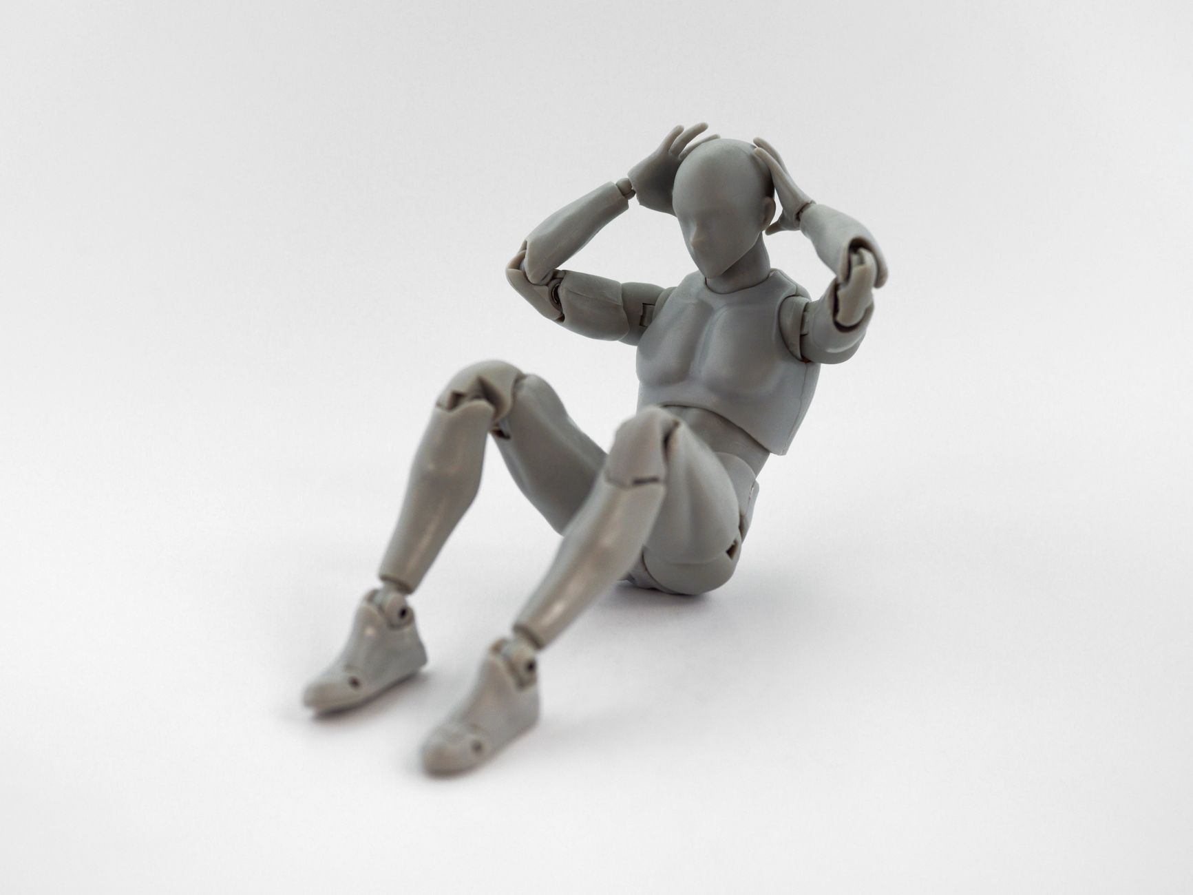 Gray plastic mannequin posed in a sit-up position on a white background.