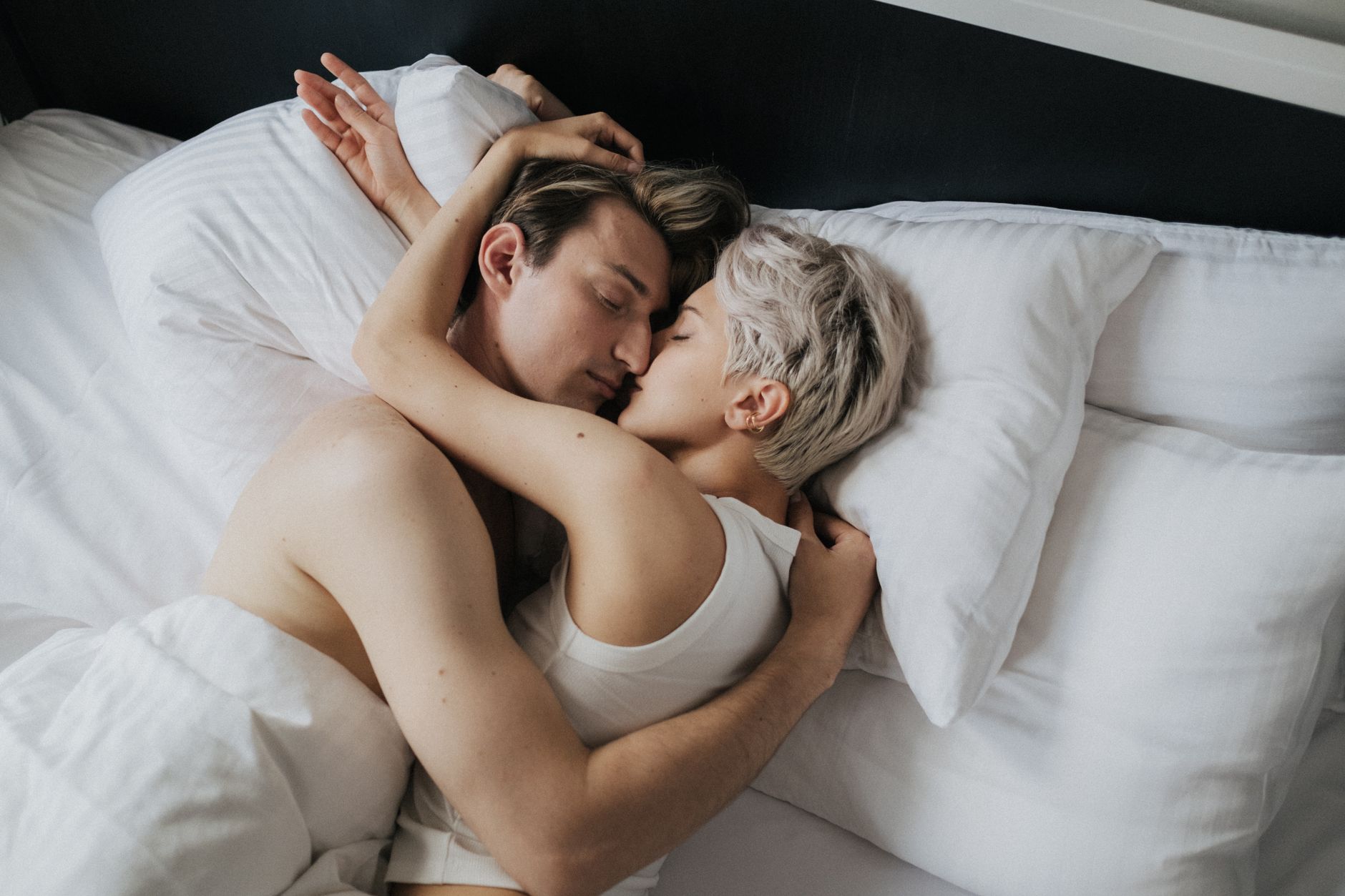 A close-up of a couple in an affectionate embrace while lying in bed.