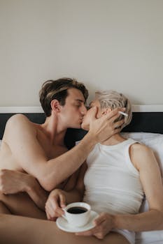 A couple sharing a tender kiss in bed, capturing a moment of love and intimacy.