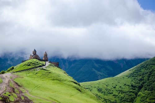Free Scenic view of Gergeti Trinity Church atop green hills in Georgia. Stock Photo