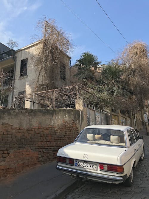 White Sedan Parked Beside Brown Concrete Building