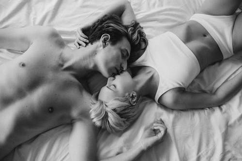 Free Grayscale Photo of a Romantic Couple Kissing on the Bed Stock Photo