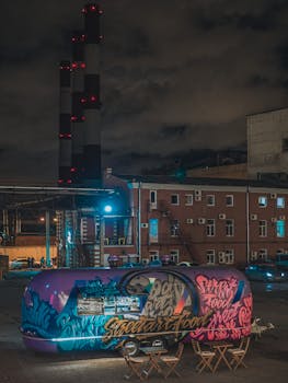 Vibrant graffiti-covered food truck in an industrial urban scene at night.