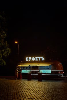 A lit food truck at night on cobblestone street, capturing a charming ambiance.