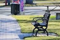 城市公园里，阳光明媚的小路上，一张孤零零的木凳营造出宁静的氛围