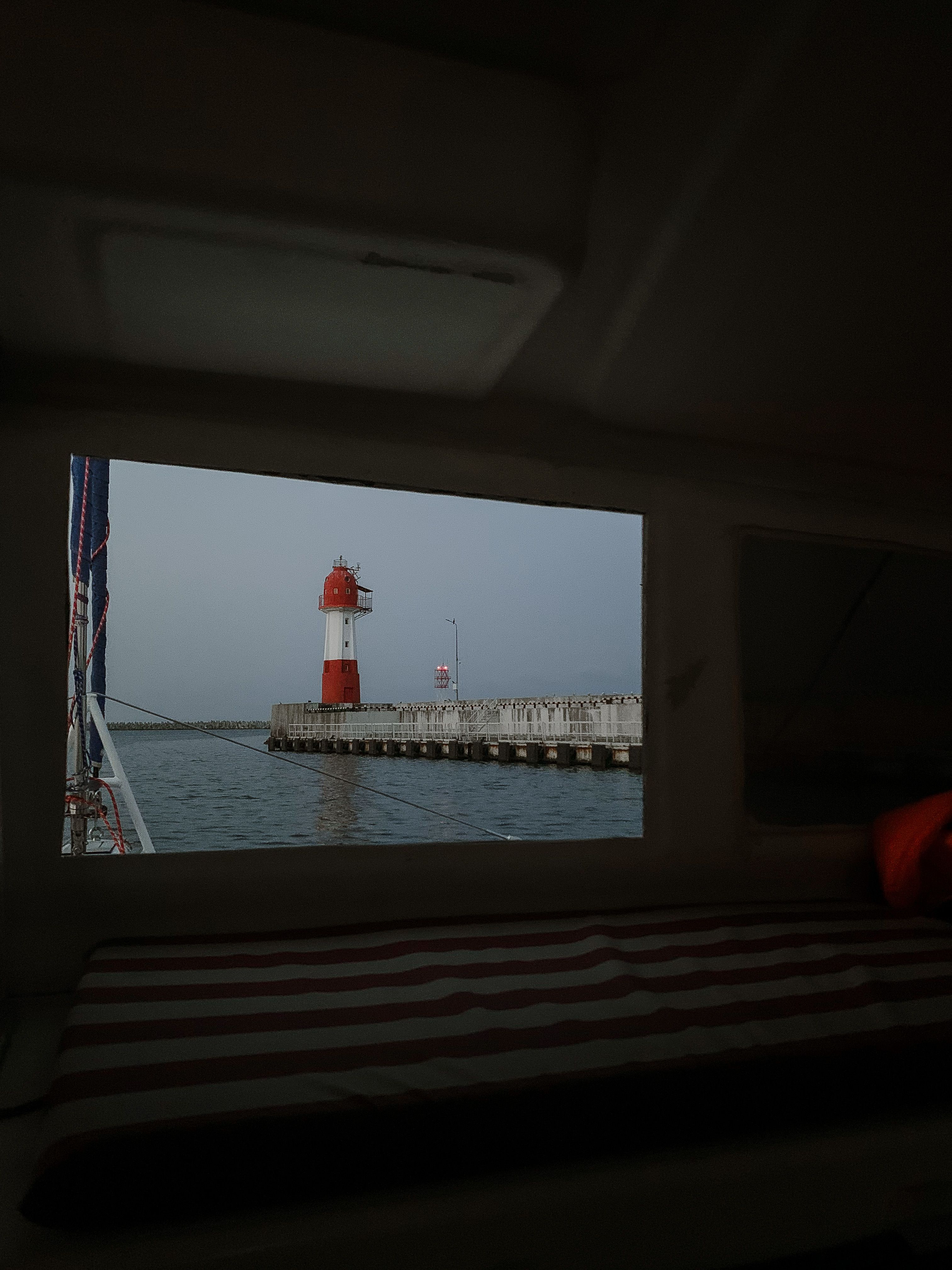 Red and White Lighthouse Near Body of Water · Free Stock Photo