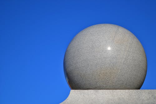 Серый шар на серой поверхности с синим фоном
