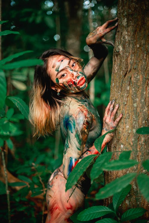 Free Woman with Body Paint Leaning on a Tree Trunk Stock Photo