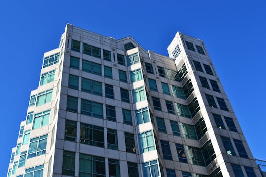 这座未来派办公楼设有玻璃窗和现代设计，矗立在晴朗的蓝天下