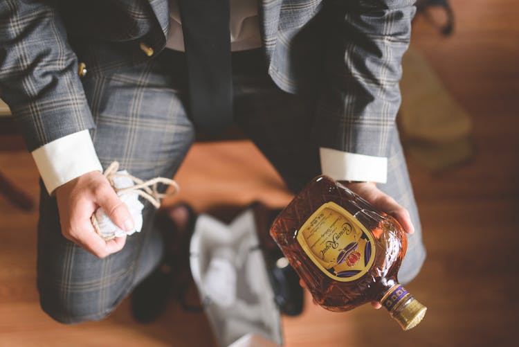 A Person In Plaid Suit Holding A Bottle Of Liquor