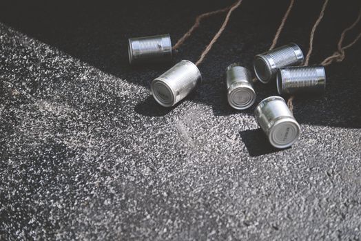 Tin cans tied with ropes placed on asphalt, creating street texture.