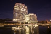 一座现代化高层建筑的夜景令人惊叹，窗户灯火通明，倒映在水中