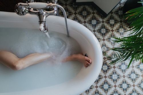 Free Top-down view of a bathtub with foam, a relaxing foot soaking moment, and stylish floor tiles. Stock Photo