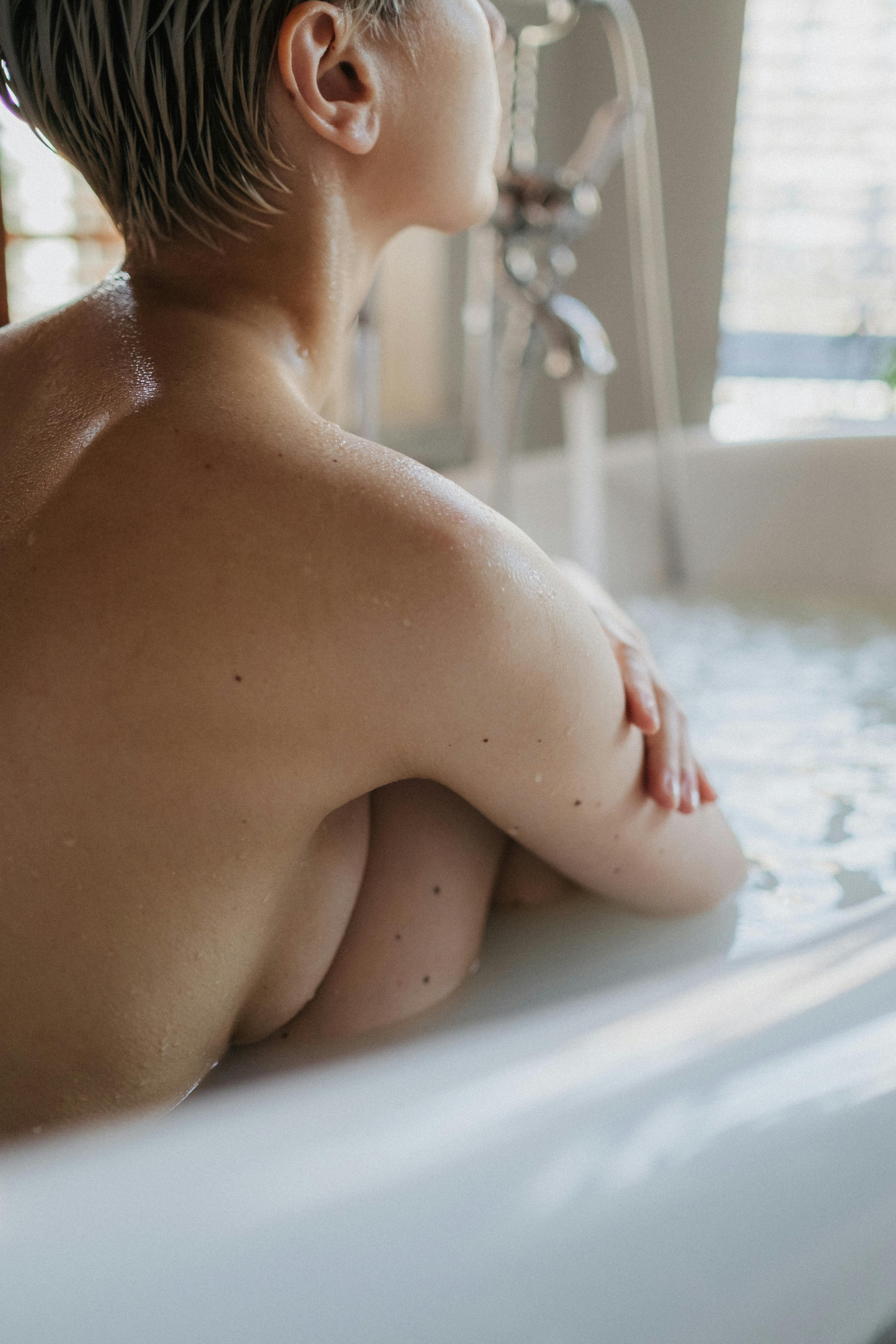 naked woman on white bathtub
