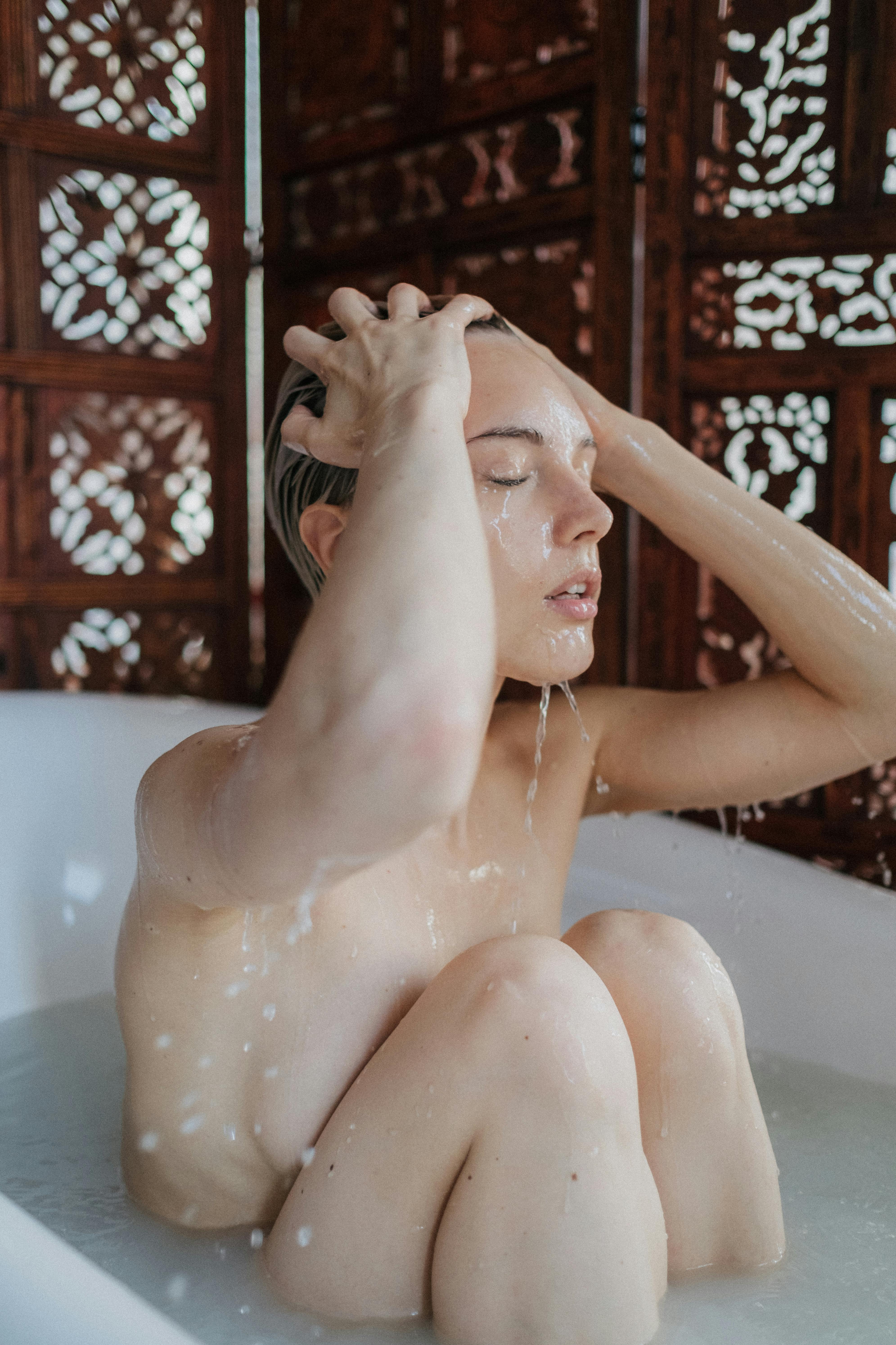 topless woman in bathtub with water