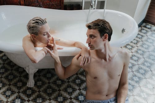 Topless Man Holding a Cigarette and a Woman in Bathtub