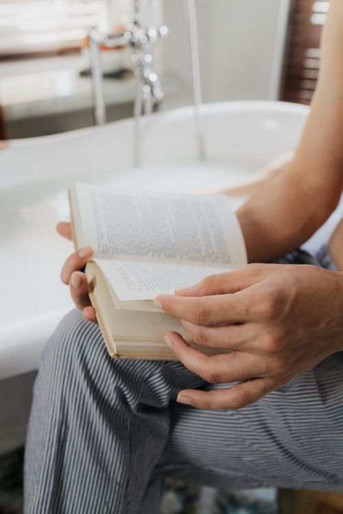 Free A person enjoys a book while relaxing in a bath, creating a serene and calming atmosphere. Stock Photo