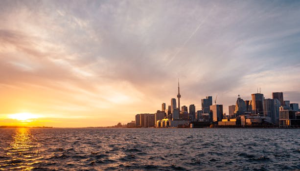 Stunning sunset view of Toronto skyline across Lake Ontario under a dramatic sky.