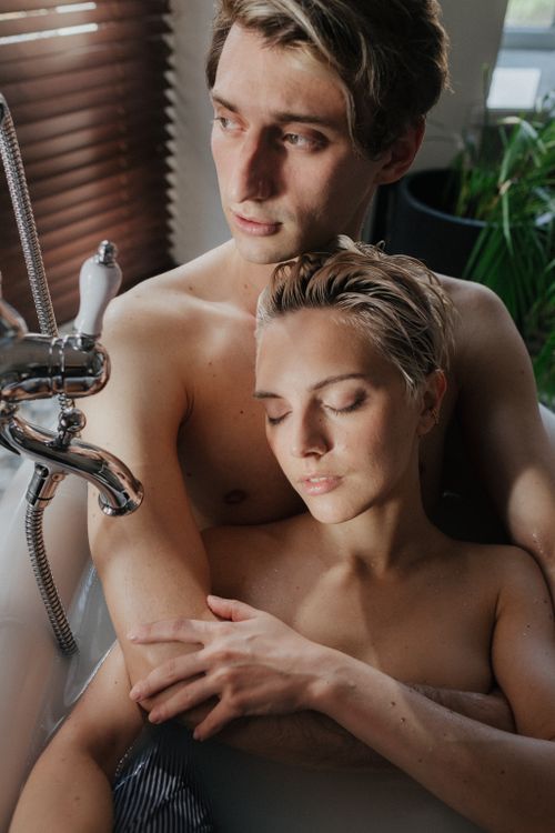 Free A romantic moment captured of a couple in a bathtub, embracing with affection. Stock Photo