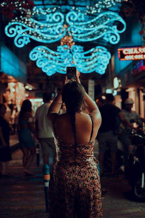 Free 
A Woman in a Floral Dress Taking a Photo with Her Smartphone Stock Photo