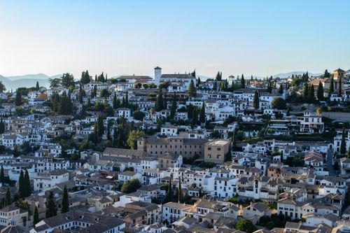 Free Expansive view of traditional architecture and green cypress trees in Granada, Spain. Stock Photo