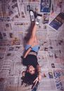 A Woman Lying Over Spread of Newspaper Sheets