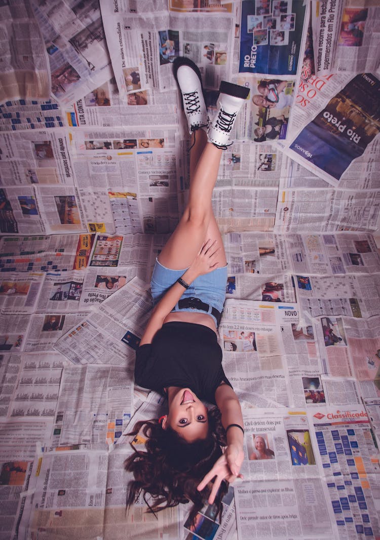 A Woman Lying Over Spread Of Newspaper Sheets