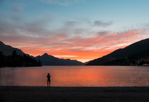 Free Silhouette Photo of Person Standing Near Body of Water Stock Photo