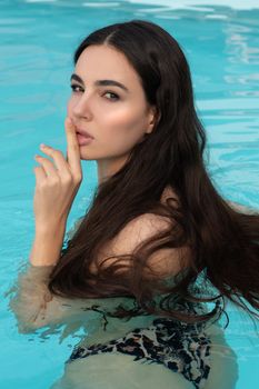 Portrait of a brunette woman in a swimming pool exuding elegance and confidence.