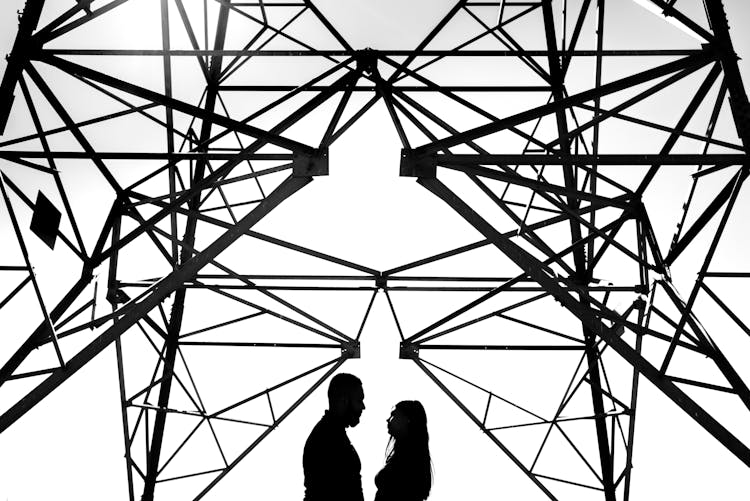 Silhouettes Of Couple Standing Under Steel Construction