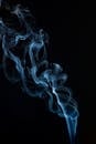 黑色背景上旋转的蓝色烟雾构成了一幅迷人的抽象图像，非常适合艺术概念