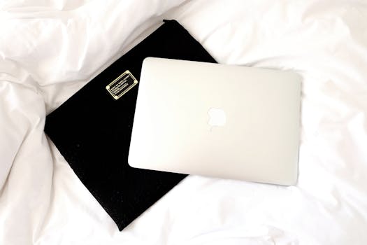 MacBook laptop resting on a bed with a black case, ideal for home office inspiration.