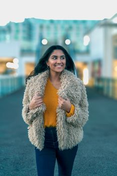 Portrait of a woman in winter clothing smiling on a London street with a blurred background.