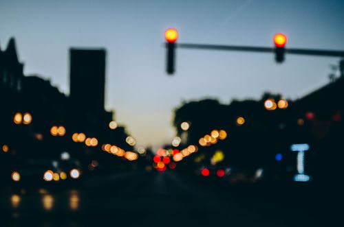 Free Stylized blurred city street scene with glowing streetlights and bokeh effect at twilight. Stock Photo