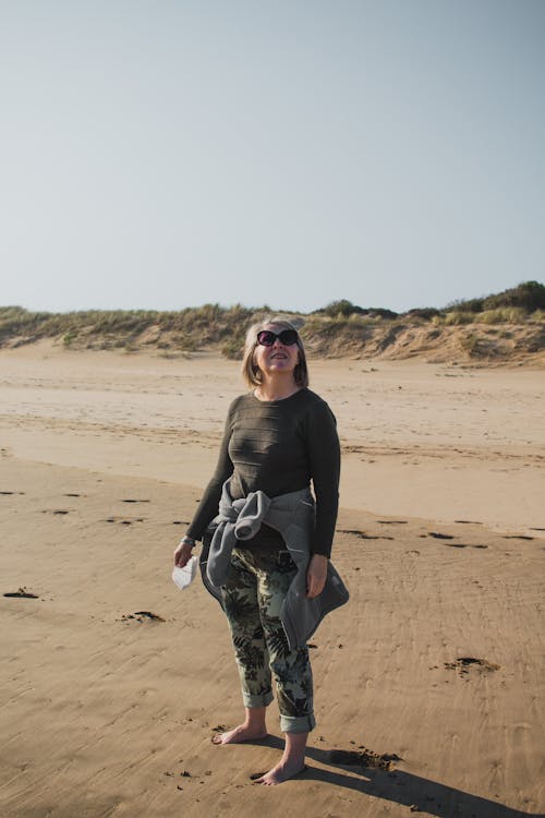 A Woman in Black Long Sleeve Shirt and Black Pants Standing on Brown Sand