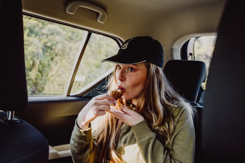 Woman in Black Hat and Brown Coat Eating Ice Cream