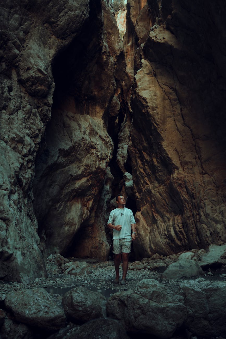 Man standing in a rugged cave surrounded by towering rock formations.