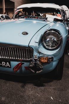 Close-up of a classic blue vintage sportscar showcasing its headlight and front design.